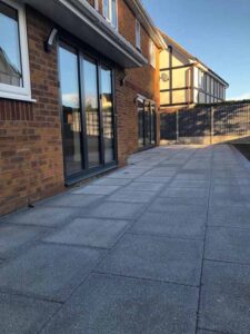 New contemporary patio laid in brick bond style with blue brick on edge border.